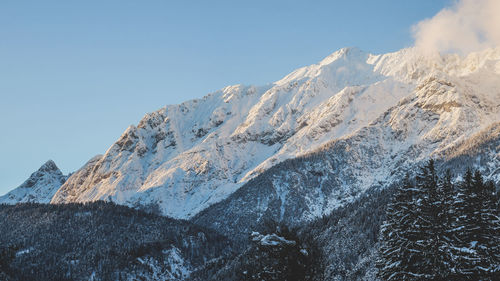 Low angle view of snowcapped mountains against clear sky