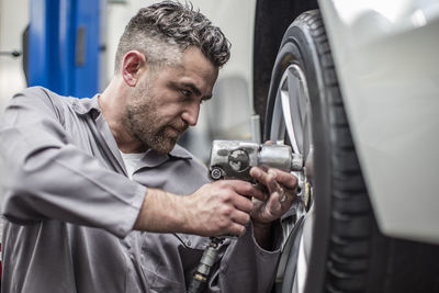 Car mechanic in a workshop changing tire