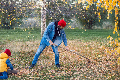 Portrait of a village man with a beard raking leaves in autumn at home