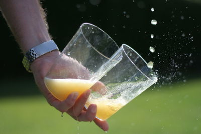 Cropped image of person holding glasses with juice