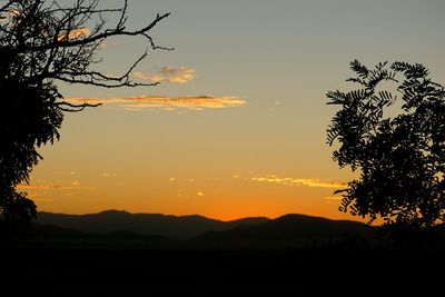 Scenic view of silhouette mountains against orange sky