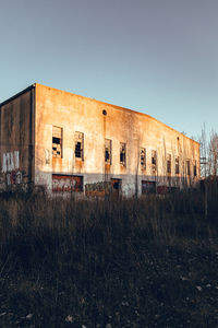 Abandoned building on field against clear sky