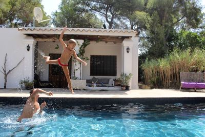 Girl with father jumping into swimming pool