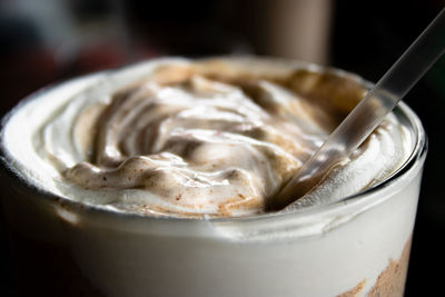 Close up of whipped cream mixed in with chocolate milkshake with a straw