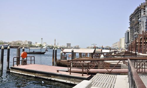 Boats moored on river by buildings against clear sky