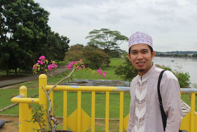 Portrait of young man wearing traditional clothing standing against sky at park