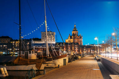 Illuminated buildings in city against clear blue sky