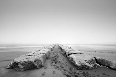 Groynes on seashore against clear sky