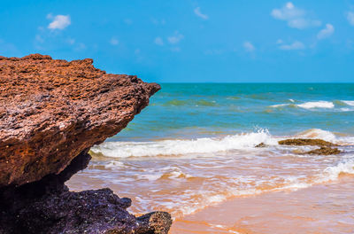 Rock formation on beach against sky