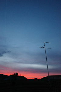 Low angle view of silhouette communications tower against sky at sunset