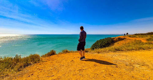 Rear view of man looking at sea against sky