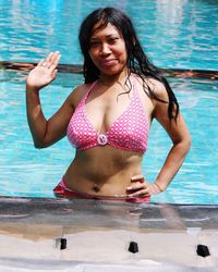 Portrait of seductive woman wearing bikini standing in swimming pool