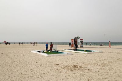 People on beach against clear sky