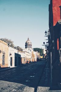 Alley amidst buildings in city against clear sky