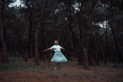 Woman standing by trees in forest