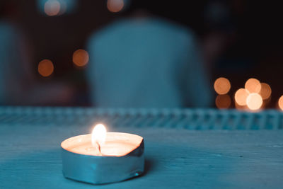 Close-up of illuminated tea light candle on table