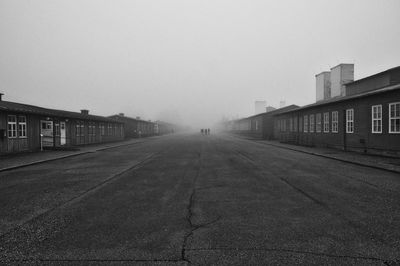 Empty road by buildings against sky in city