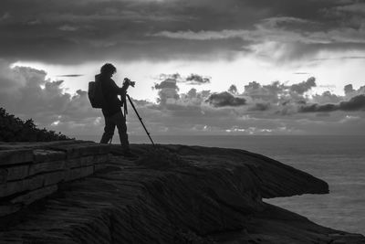 Man photographing at sea shore against sky