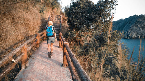 Full length of woman walking on footpath by lake and trees