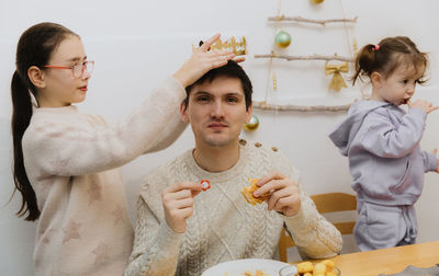 A girl puts a crown on an adult guy who ate a royal galette.