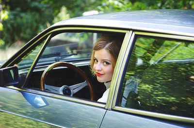Smiling young woman looking through car window
