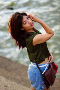 Portrait of young woman standing against lake