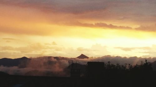 Silhouette house against sky at sunset