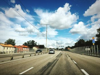 Cars on road against sky in city