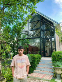 Portrait of young woman standing against plants