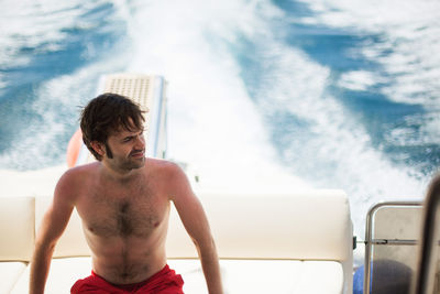 Rear view of shirtless man standing in sea