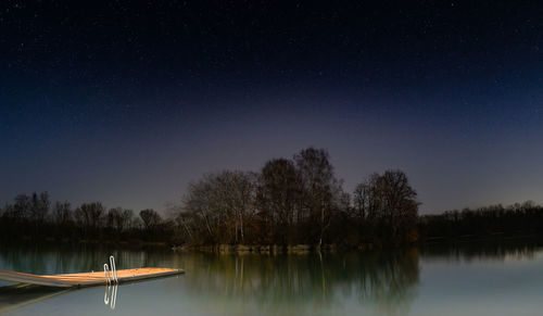 Scenic view of lake against clear sky at night