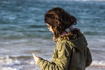 Rear view of woman with umbrella standing at beach