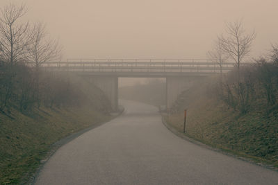Empty road by bridge against sky