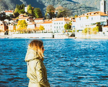 Side view of woman standing by river in city