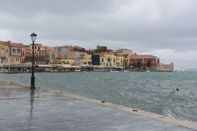 View of buildings by sea against cloudy sky