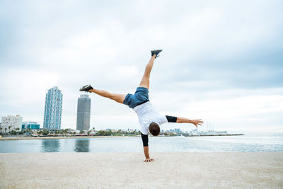 Full length of woman jumping at beach against sky