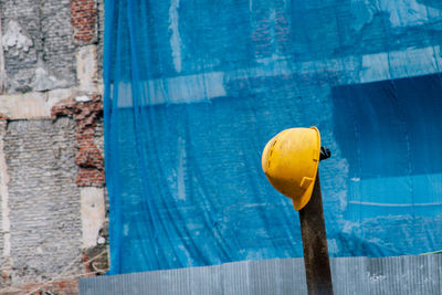 Yellow hardhat hanging on pole at construction site