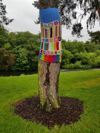 Multi colored tree trunk on field against trees