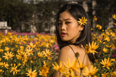 Portrait of woman by yellow blooming flowers