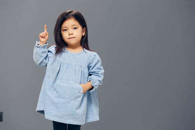 Girl pointing against gray background