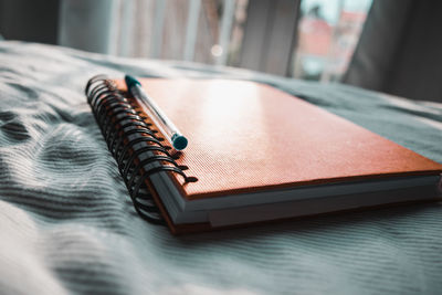 Close-up of book with pen on bed at home