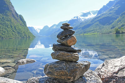 Stack of rocks in lake by mountains against sky