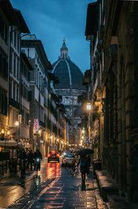 People on street amidst buildings in city at night