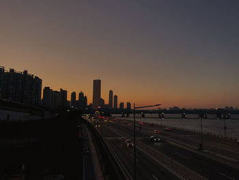 Railroad tracks by buildings against sky during sunset