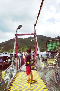 Rear view of woman with umbrella against sky