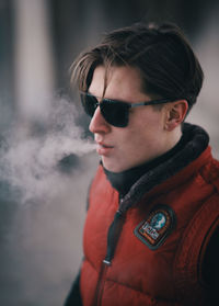 Young man wearing sunglasses smoking in corridor