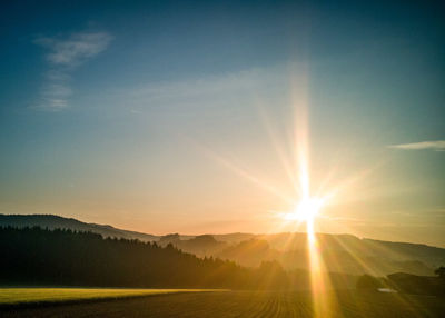 Scenic view of landscape and mountains against sky during sunrise