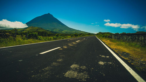 Road by mountains against blue sky