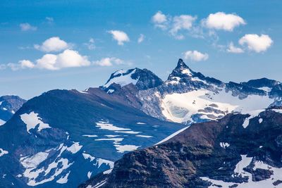 Scenic view of snow covered mountains against blue sky