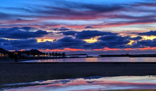 Scenic view of sea against dramatic sky during sunset